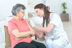  La imagen muestra a una enfermera realizando el procedimiento de administración de tratamiento parenteral mediante vía subcutania a una paciente en la comodidad de su hogar. 