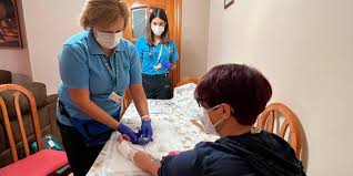  La imagen muestra a una enfermera realizando el procedimiento de administración de tratamiento parenteral mediante vía endovenosa a un niño en la comodidad de su hogar. 